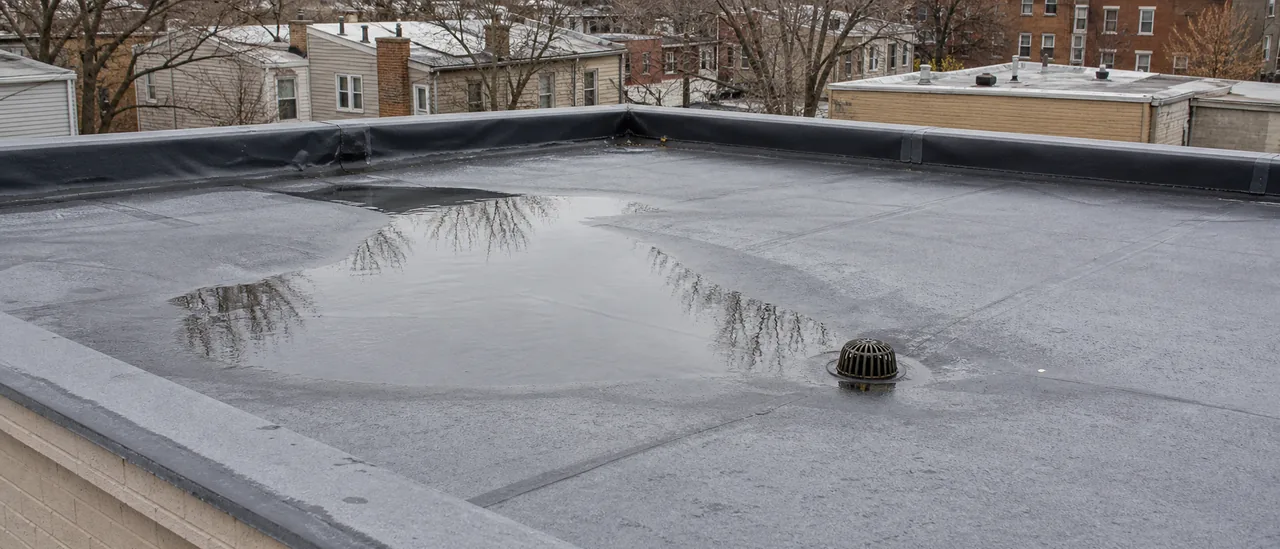 Educational illustration explaining what causes ponding water on a flat roof.